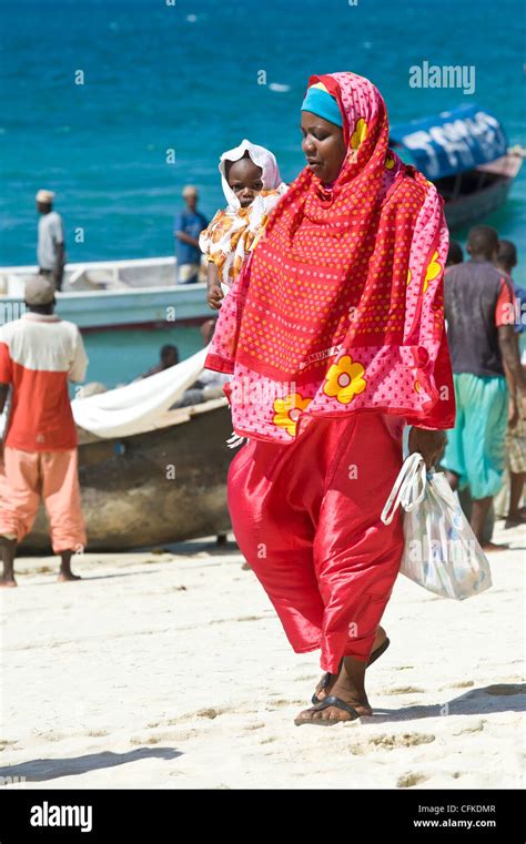 Swahili Woman With Child In Traditional Dresses Walking On The Beach In