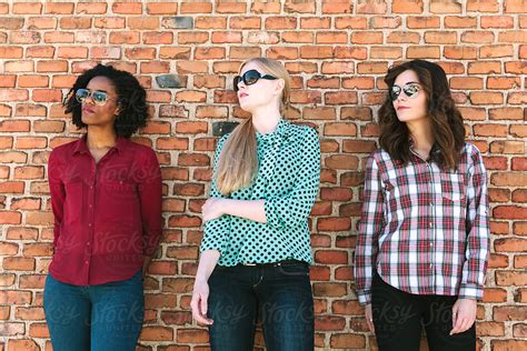 «three Young Women Leaning On A Brick Wall Del Colaborador De Stocksy