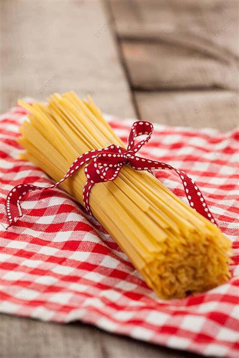 Red Ribbon Tied Around A Bunch Of Uncooked Spaghetti Photo Background