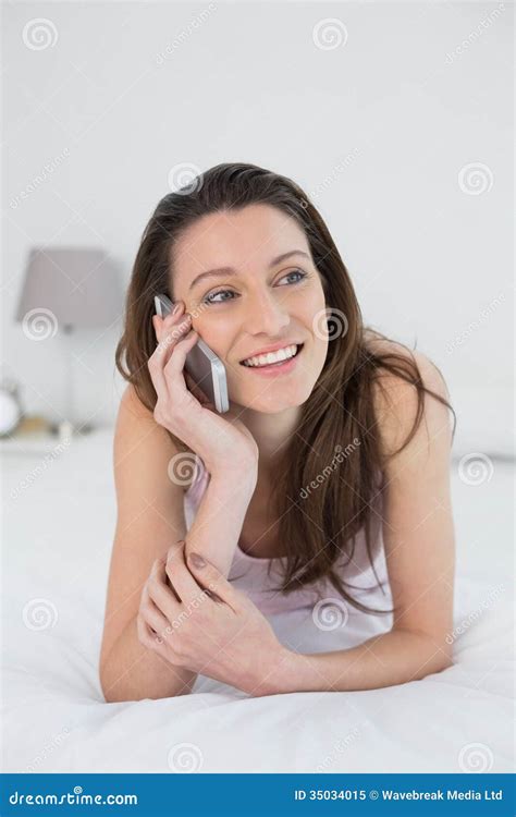 Mulher De Sorriso Que Usa O Telefone Celular Na Cama Imagem De Stock