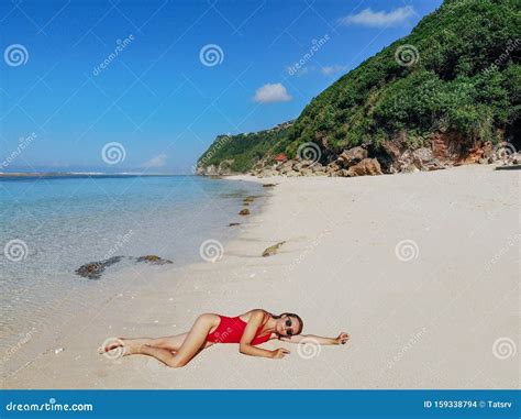 Woman In Red Bikini Relaxing On White Sand Tropical Beach With Blue Clear Water And Jungle Bali