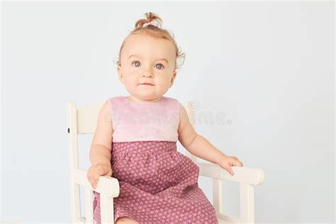 La Belle Petite Fille Dans Une Robe S Assied Sur Une Chaise Blanche