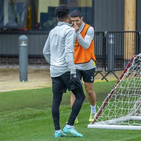 Two Soccer Players Are Talking To Each Other In Front Of The Goalie S Net