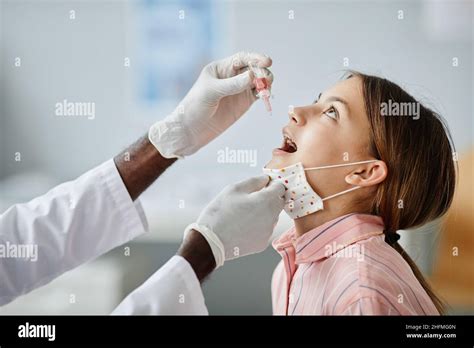 Side View Of Doctor Dropping Liquid In Child Mouth During Oral