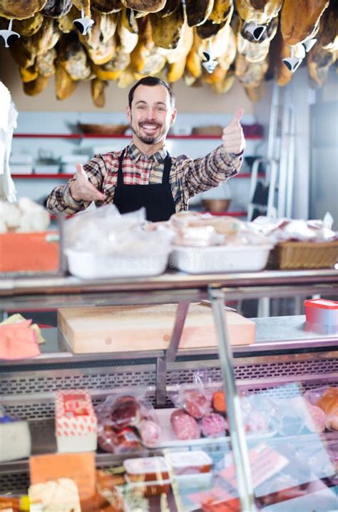 Attractive Male Shop Assistant Demonstrating Sorts Of Meat In Shop