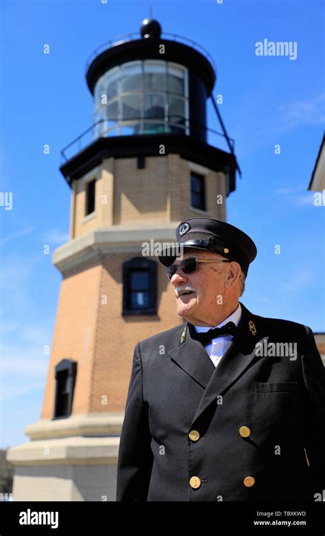 A male guide in traditional lighthouse keepers' uniform posing by the Split Rock Lighthouse ...