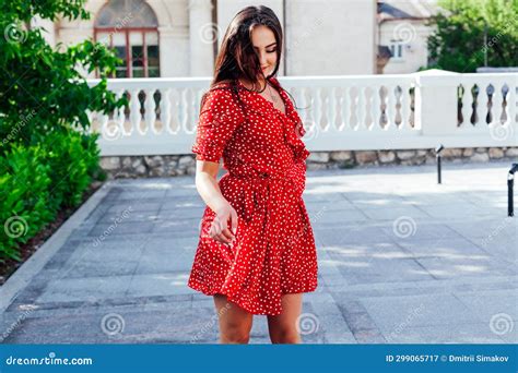 Beautiful Brunette Woman In Red Polka Dot Dress Walks The Streets Of