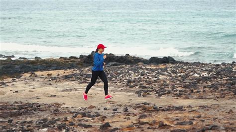 Woman Runs Along The Stony Shore Of The Ocean Healthy Active Lifestyle