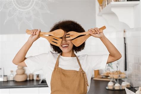 Une Femme Au Foyer Africaine En Tablier Pose Avec Des Spatules Pour