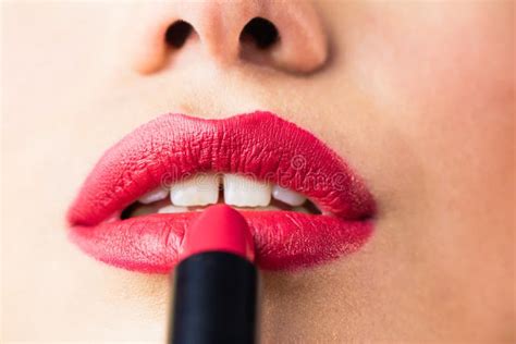 Beautiful Woman Applying Red Lipstick On Lips Against Black Background