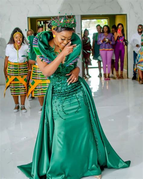 A Woman In A Green Dress Standing On A White Floor With Other People