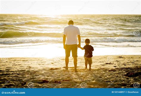 Happy Father Holding Hand Of Little Son Walking Together On The Beach