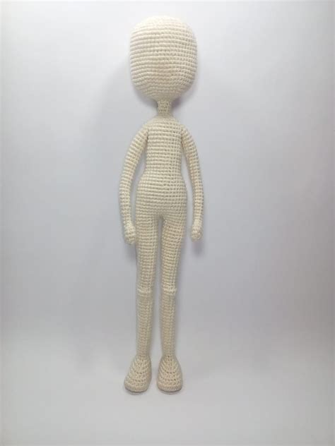 A White Knitted Doll Is Posed On A Gray Background