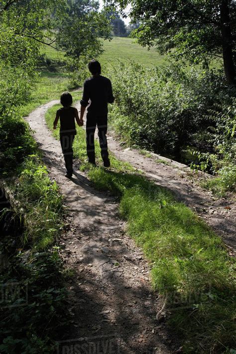 Father And Son Walking Down Country Road Stock Photo Dissolve