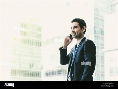 Businessman Using Mobile Phone Near Office Window At Office Building