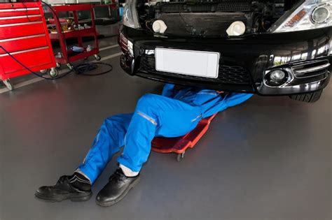 Premium Photo Mechanic In Blue Uniform Lying Down And Working Under