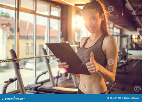 Personal Trainer With Clipboard Showing Thumbs Up In Gym Stock Image