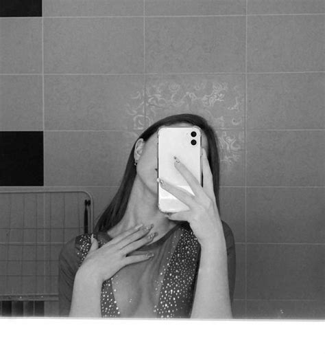 A Woman Taking A Selfie In The Bathroom Mirror With Her Phone Up To Her Face