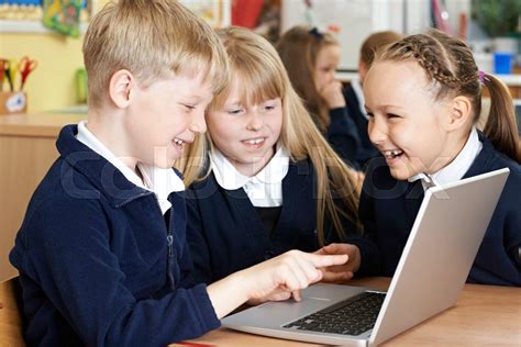 Group Of Elementary School Children Working Together In Computer Class