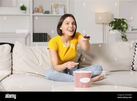 Happy Woman Eating Popcorn While Watching Tv On Sofa At Home Stock