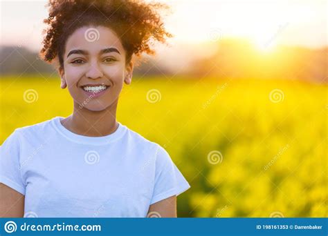 Mixed Race African American Girl In A Field Of Yellow Flowers At Sunset