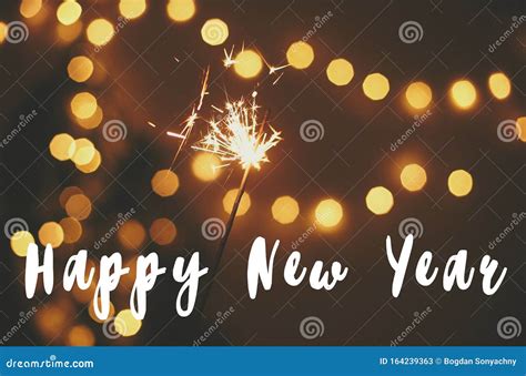 Happy New Year Text Sign On Glowing Sparkler In Hand On Background Of