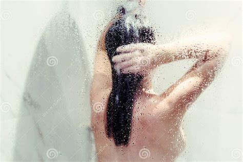Silhouette of Naked Beautiful Woman Washing Hair in Shower Behind Wet