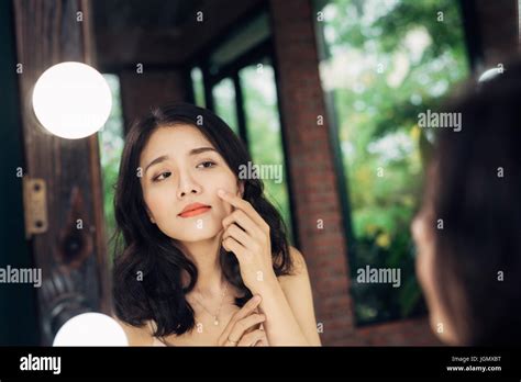 Pretty Happy Asian Woman Watching On Herself In A Big Mirror At Home