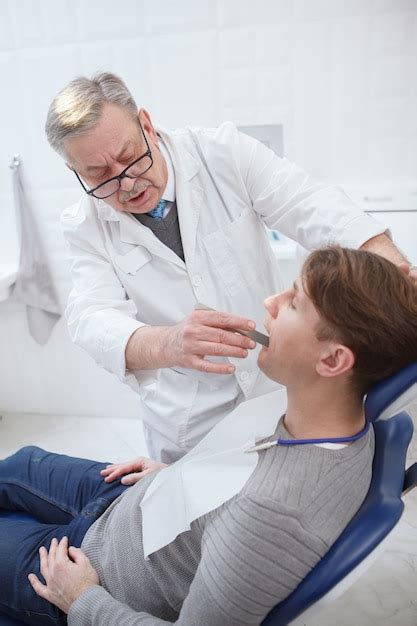 Foto vertical de um dentista idoso trabalhando em sua clínica