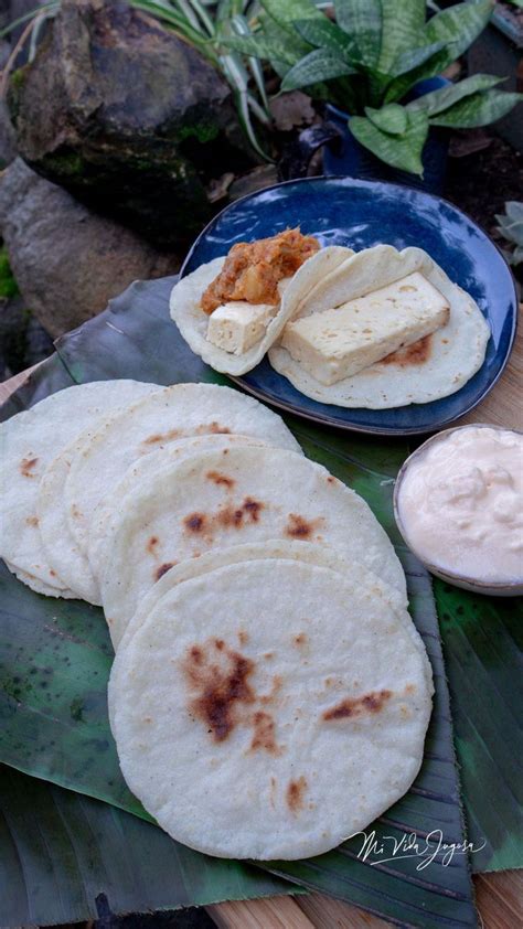 Some Tortillas Are Sitting On A Plate With Sauces And Leaves Next To Them