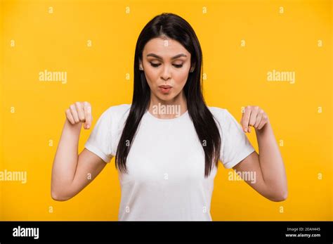 Pretty Caucasian Brunette Girl In A White T Shirt Points Fingers Down