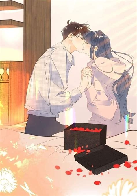 A Man And Woman Kissing In Front Of A Box With Petals On The Table Next