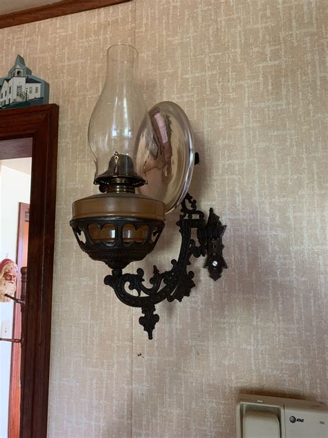 This Is A Kerosene Lamp In A Bracket Hanging On The Wall With A Metal