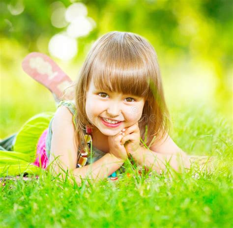 Petite Fille De Sourire Se Trouvant Sur L Herbe Verte Photo Stock