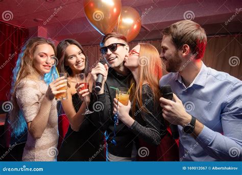 Group Of Young People Singing Into Microphone In Karaoke Bar Stock