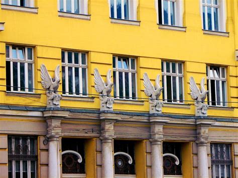 An Old Yellow Building With Pigeons On The Windows