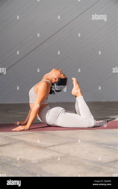 A Brunette Woman Dressed In Sportswear Performing King Cobra Yoga Pose