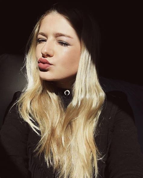 A Woman With Long Blonde Hair Blowing Out Her Tongue