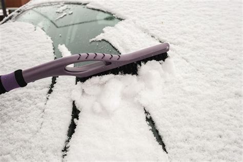 Premium Photo Hand Removing Snow From Car With A Brush