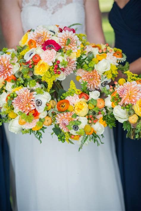 The Bridesmaids Are Holding Their Bouquets With Orange Yellow And