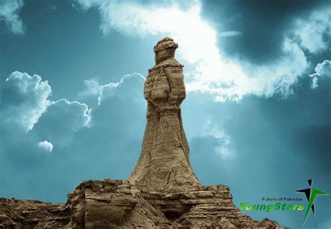 the statue is standing in front of some rocks and blue sky with clouds ...