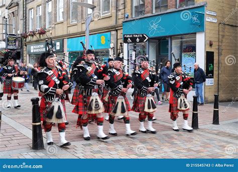 Several Men Dressed With Typical Scottish Kilts Playing The Highland