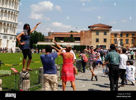 Some Tourists Posing For The Typical Photo In The Leaning Tower Of Pisa