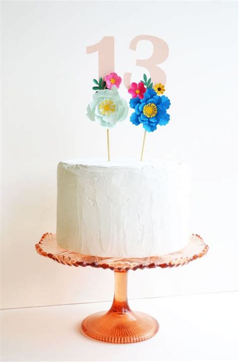 There Is A White Cake With Flowers On Top And The Number Thirteen On It