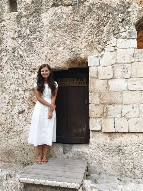 A Woman Standing In Front Of A Door On The Side Of A Stone Building