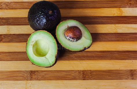 Aguacate Cortado A La Mitad Con Una Piedra Sobre Una Tabla De Madera