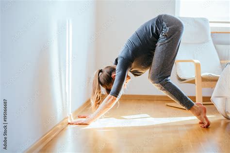 Beautiful photo of young barefoot woman in gray sportswear practicing ...