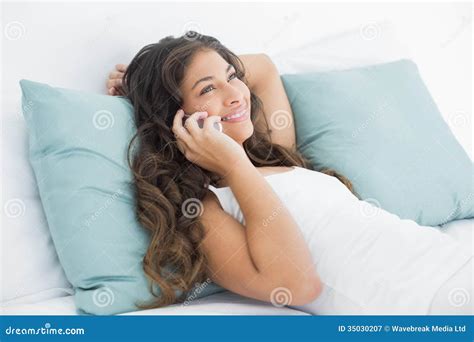 Jovem Mulher Que Usa O Telefone Celular Na Cama Imagem De Stock