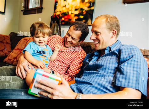 Gay Fathers Playing With Baby Son On Sofa Stock Photo Alamy