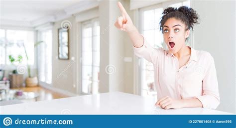 Wide Angle Of Beautiful African American Woman With Afro Hair Pointing With Finger Surprised